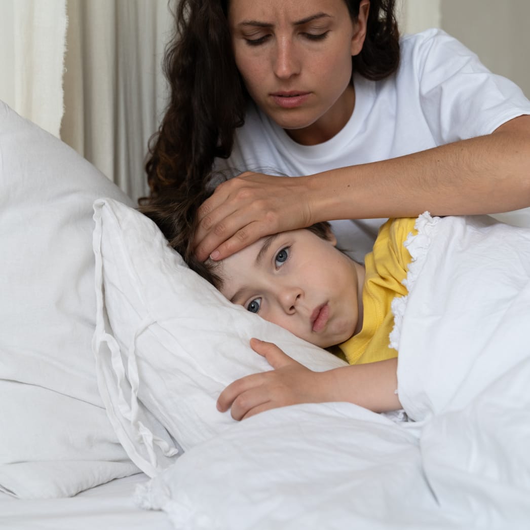 Mother taking care of sick child in bed