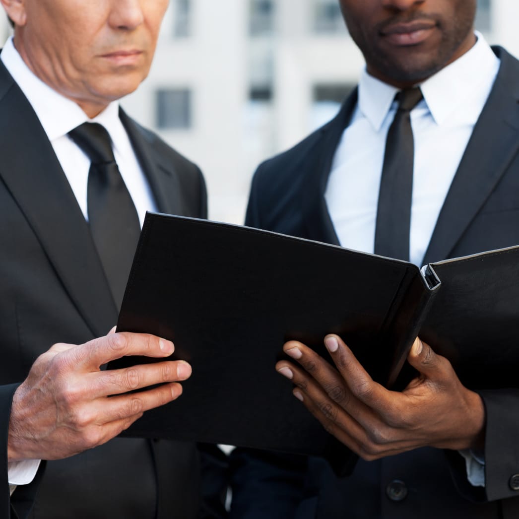 Two businessmen looking at a binder of documents together